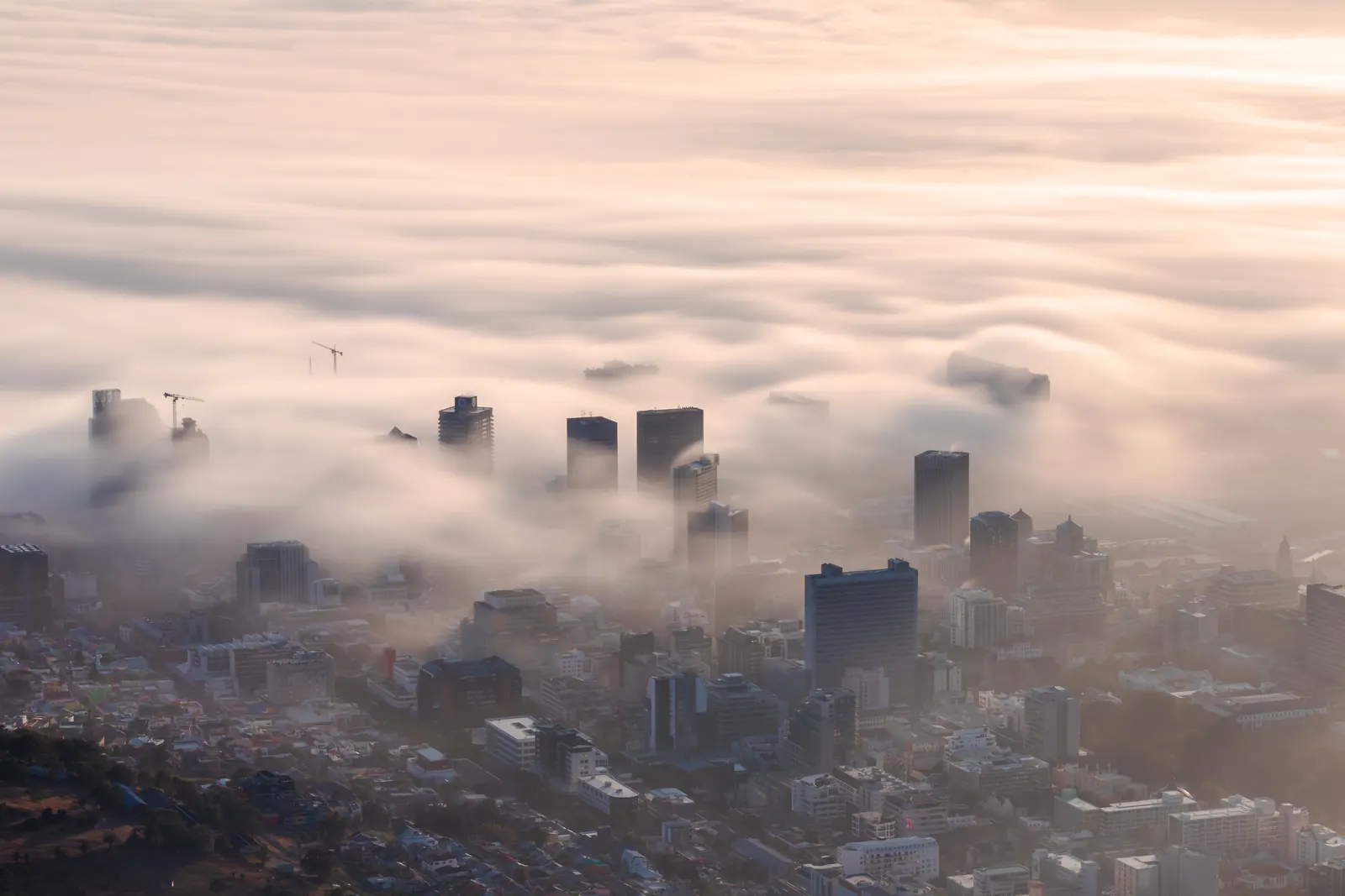 City towers barely breaking the surface of deep, heavy fog